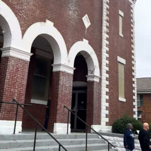 Steps lead to the entrance of Brown Chapel, with brick and plaster arches over the doors.