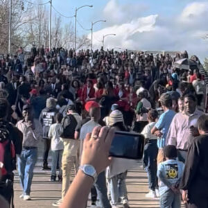 The marching crowd crosses the bridge and the two crowds converge.
