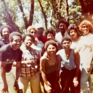 A crowd of people smiling in an old yellowed photograph.