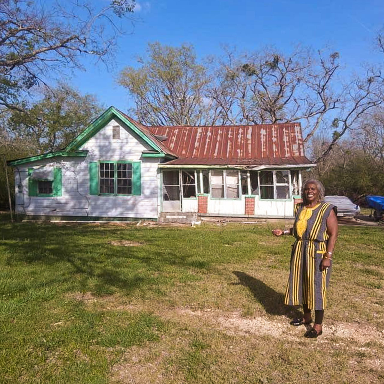 A woman stands in front of a house.
